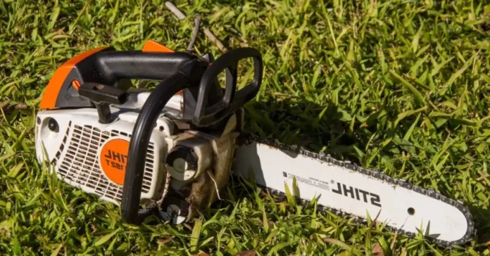 Mechanic fixing mo39 Stihl gas leak by replacing cracked fuel line on a chainsaw outdoors.