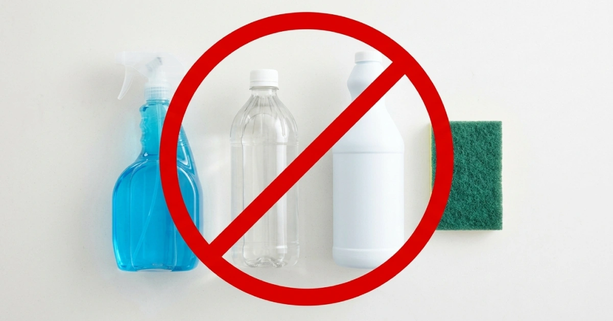 Vinegar, bleach, glass cleaner, and abrasive sponge lined up as cleaners to avoid on quartz countertops